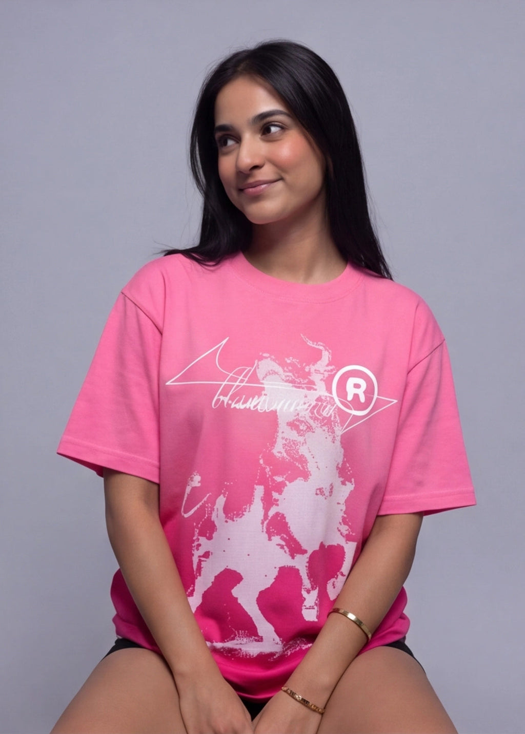 Woman wearing a pink t-shirt with a graphic design on a gray background